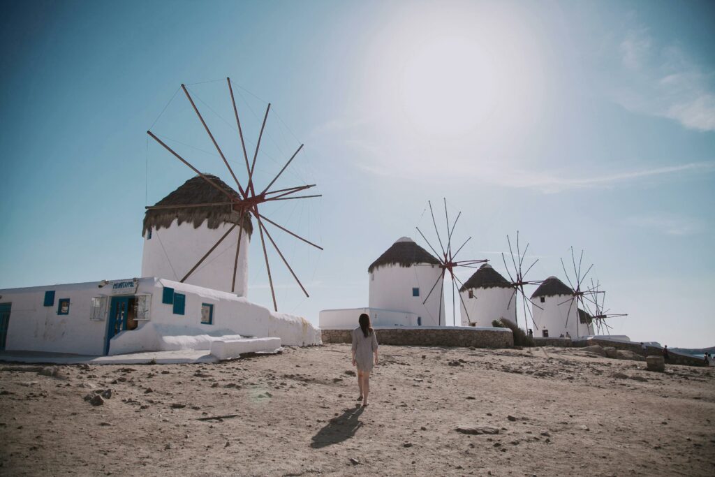 Explore the iconic windmills of Mykonos, Greece, on a sunny day, capturing their historical charm.